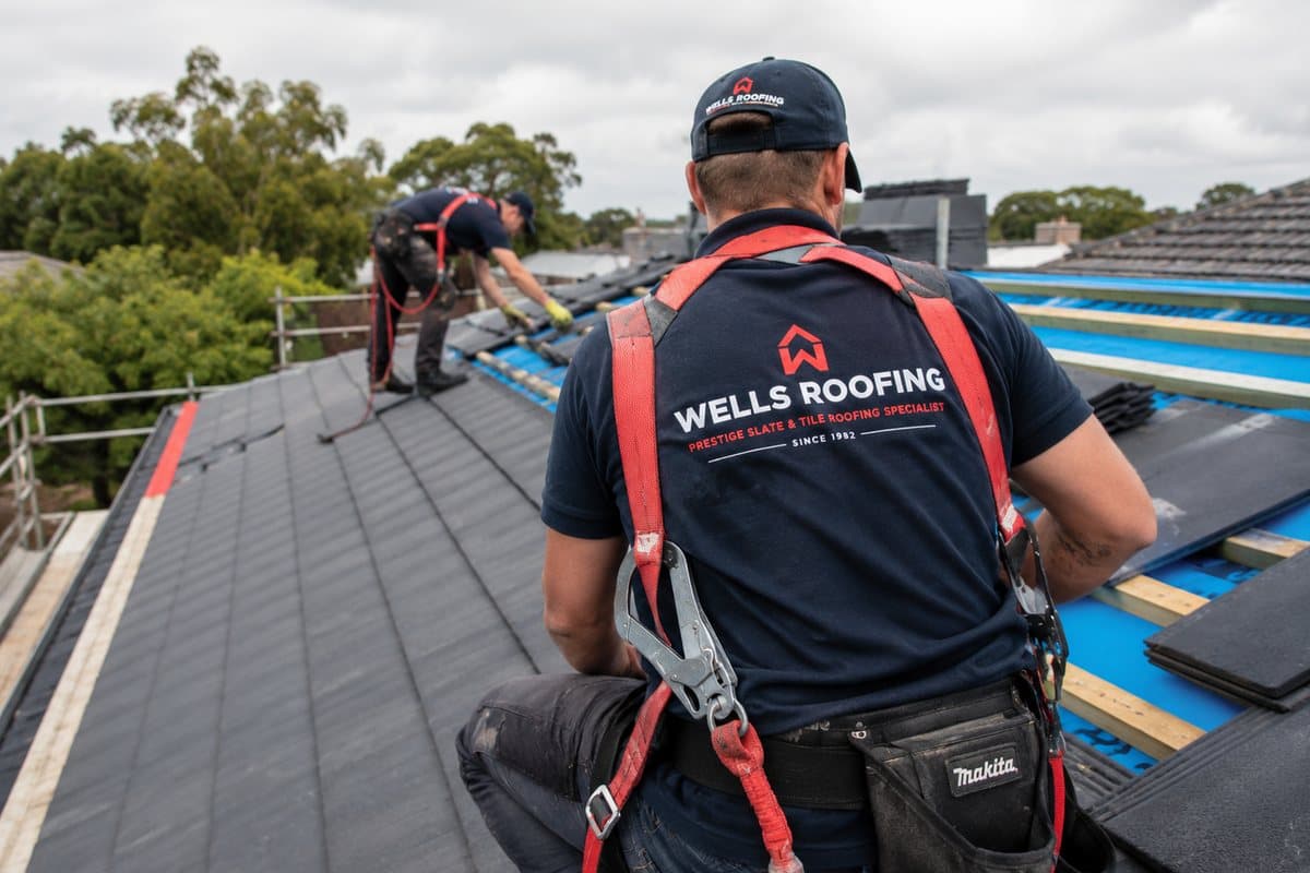 Wells Roofing crew in safety harnesses working on a slate re-roof