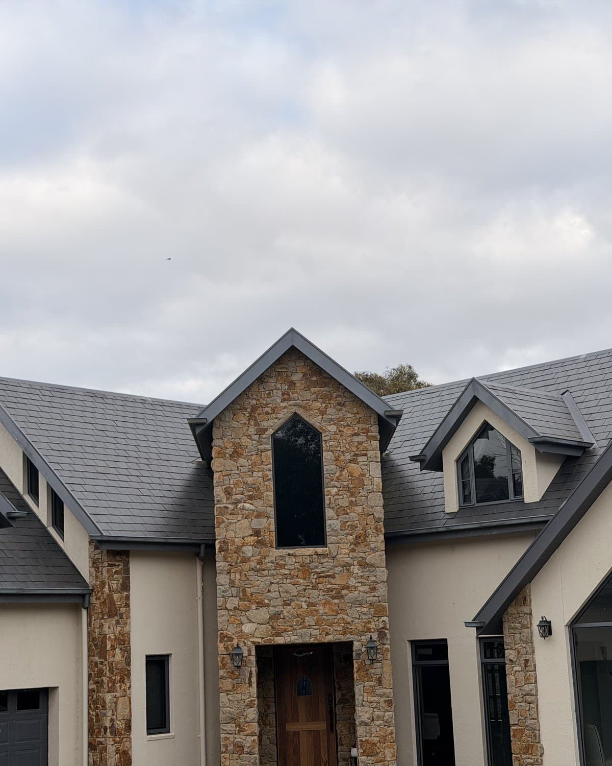 Completed natural slate roof on a stone and render home