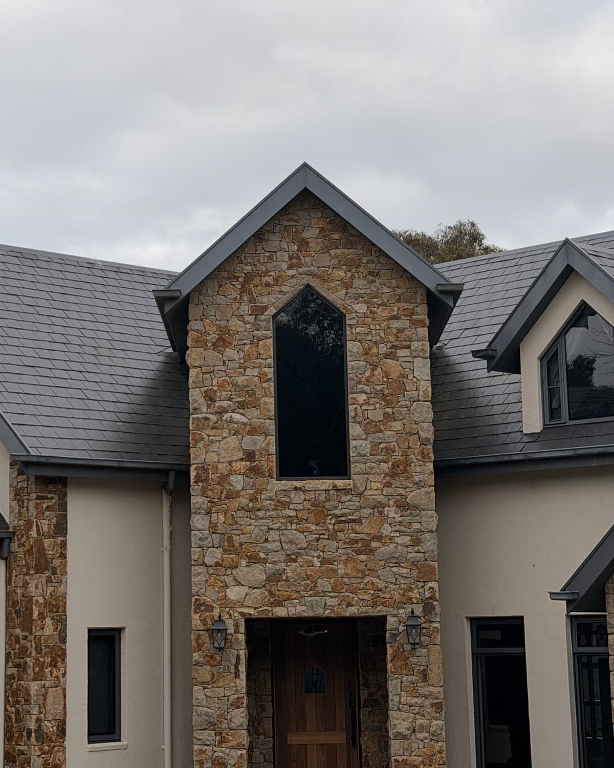 Slate roof on a stone and render home by Wells Roofing, showing the entry gable, dormers and flashing detail