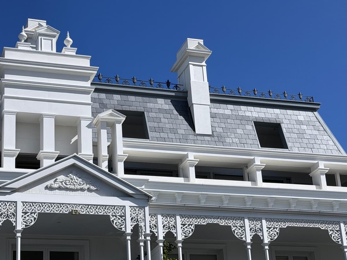 Close view of the slate between the dormers and a rendered chimney