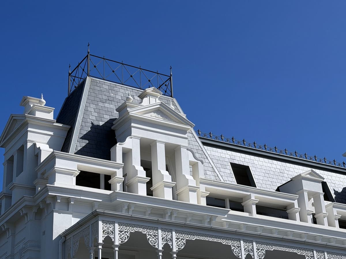 Slate mansard with dormer windows beneath iron roof cresting